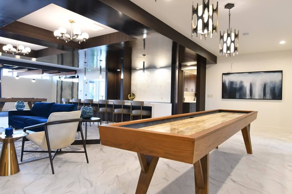 Large boardgame table in a modern clubhouse community featuring cushioned chairs and upgraded light fixtures.